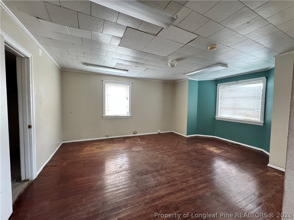202 Main Street Hamlet, NC 28345 - Photo 2 of 7 an empty room with wooden floor and windows
