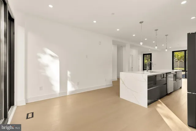 a large kitchen with stainless steel appliances a large counter top a refrigerator and a more window