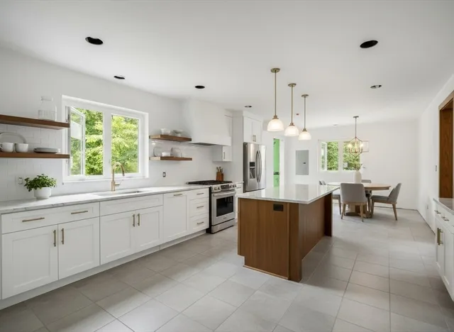 a kitchen with kitchen island granite countertop a sink counter top space appliances and a window
