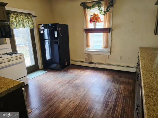 a view of a refrigerator in wooden floor and windows in a room