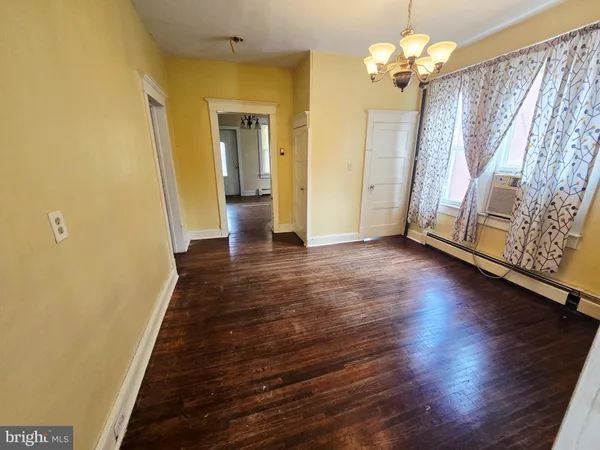 a view of a hallway with wooden floor and a large mirror
