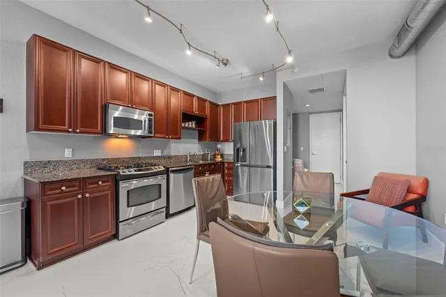a kitchen with stainless steel appliances kitchen island hardwood floor and a refrigerator