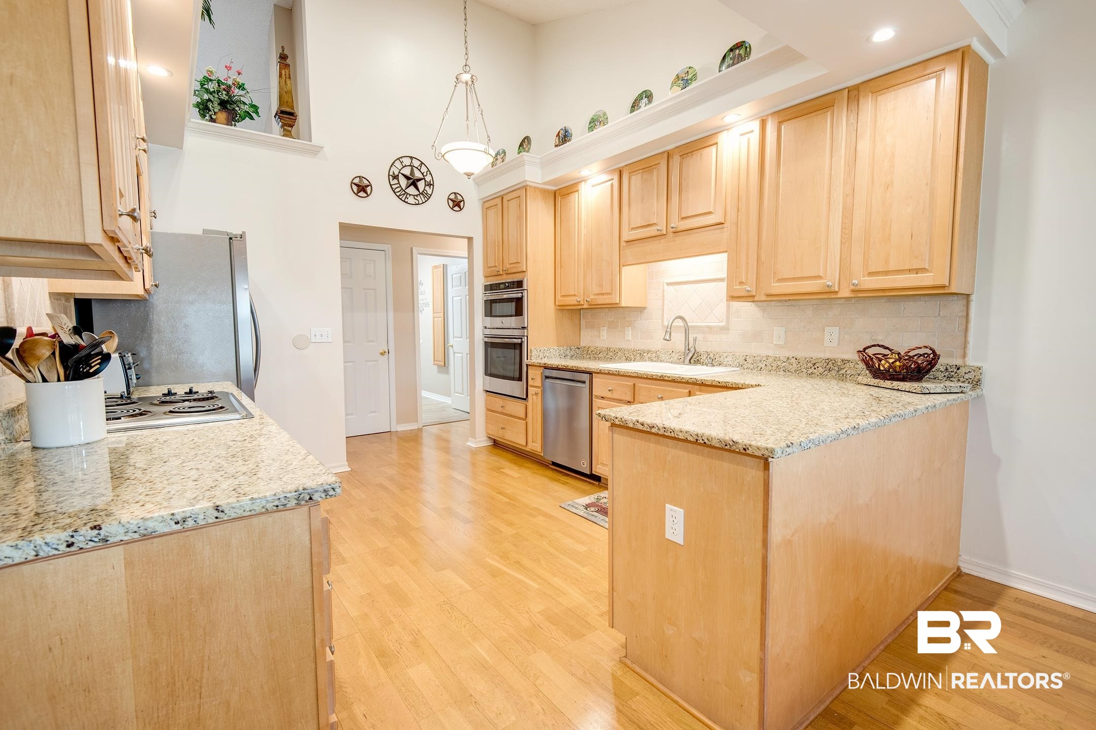 12626 Hunters Chase Foley, AL 36535 - Photo 14 of 40 Kitchen with light wood finish cabinetry, backsplash, light stone counters, light wood finished floors, and a high ceiling