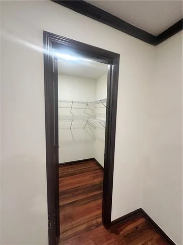 a view of an empty room with wooden floor and window