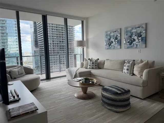 a living room with furniture a flat screen tv and kitchen view