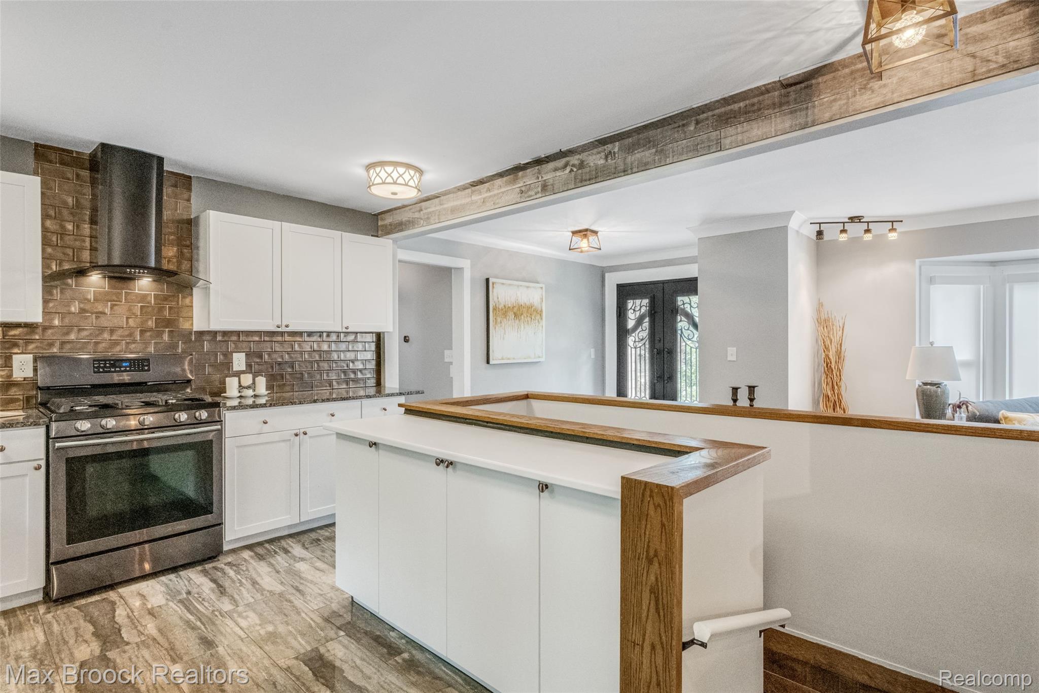 2905 Lahser Road Bloomfield Hills, MI 48304 - Photo 10 of 28 Kitchen featuring white cabinetry, bronze tile backsplash, stainless steel range with hood, wood-finish flooring, and a peninsula with a light-toned countertop