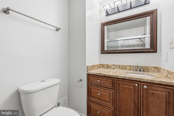 a bathroom with a granite countertop toilet sink and mirror