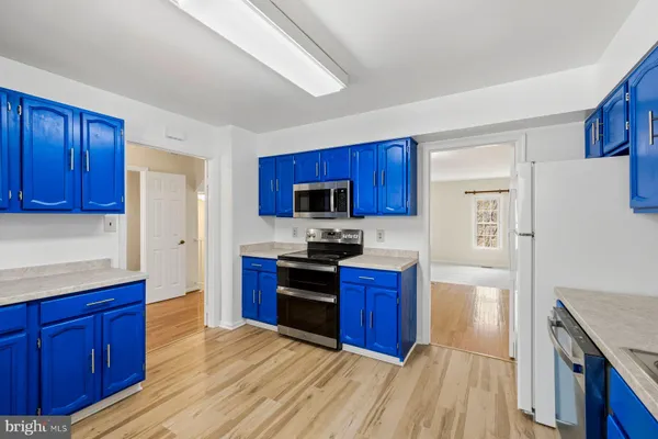 a kitchen with stainless steel appliances granite countertop wooden cabinets a stove a sink and dishwasher with wooden floor