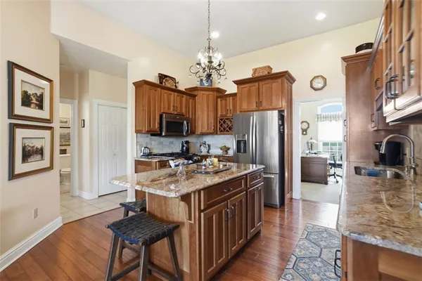 a kitchen with stainless steel appliances granite countertop a refrigerator a stove oven a sink dishwasher and white cabinets with wooden floor