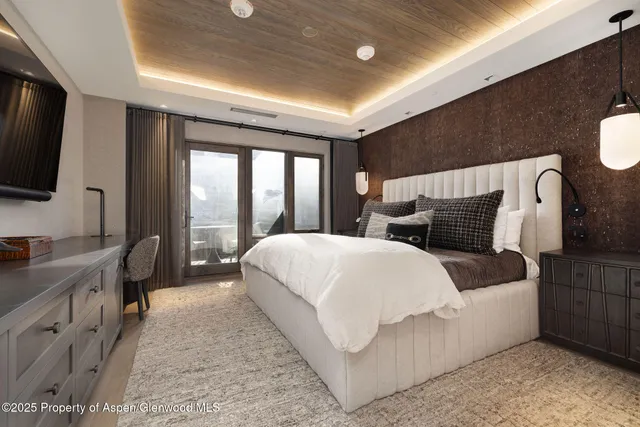 a spacious bedroom with a large bed and a flat tv screen on dresser