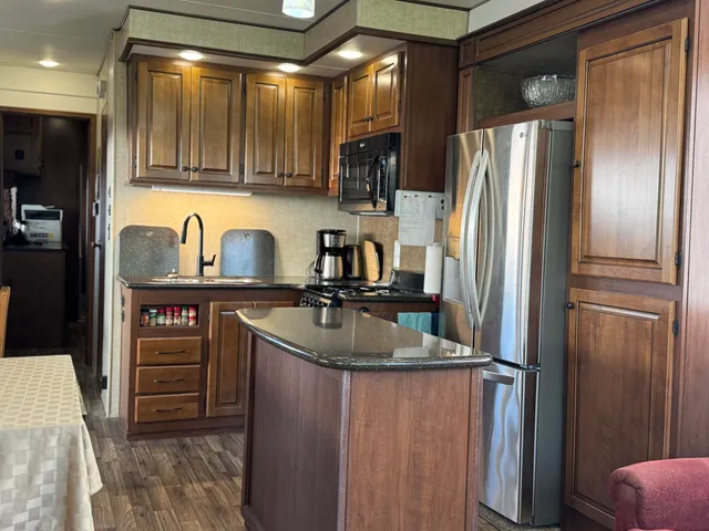 a metallic refrigerator and stove sitting inside of a kitchen