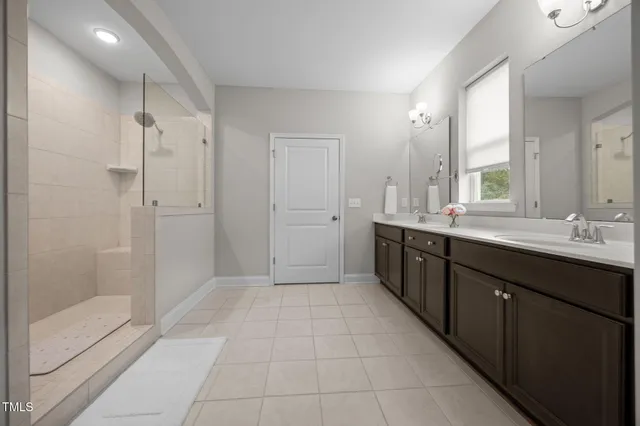 a spacious bathroom with a double vanity sink a mirror and a bathtub