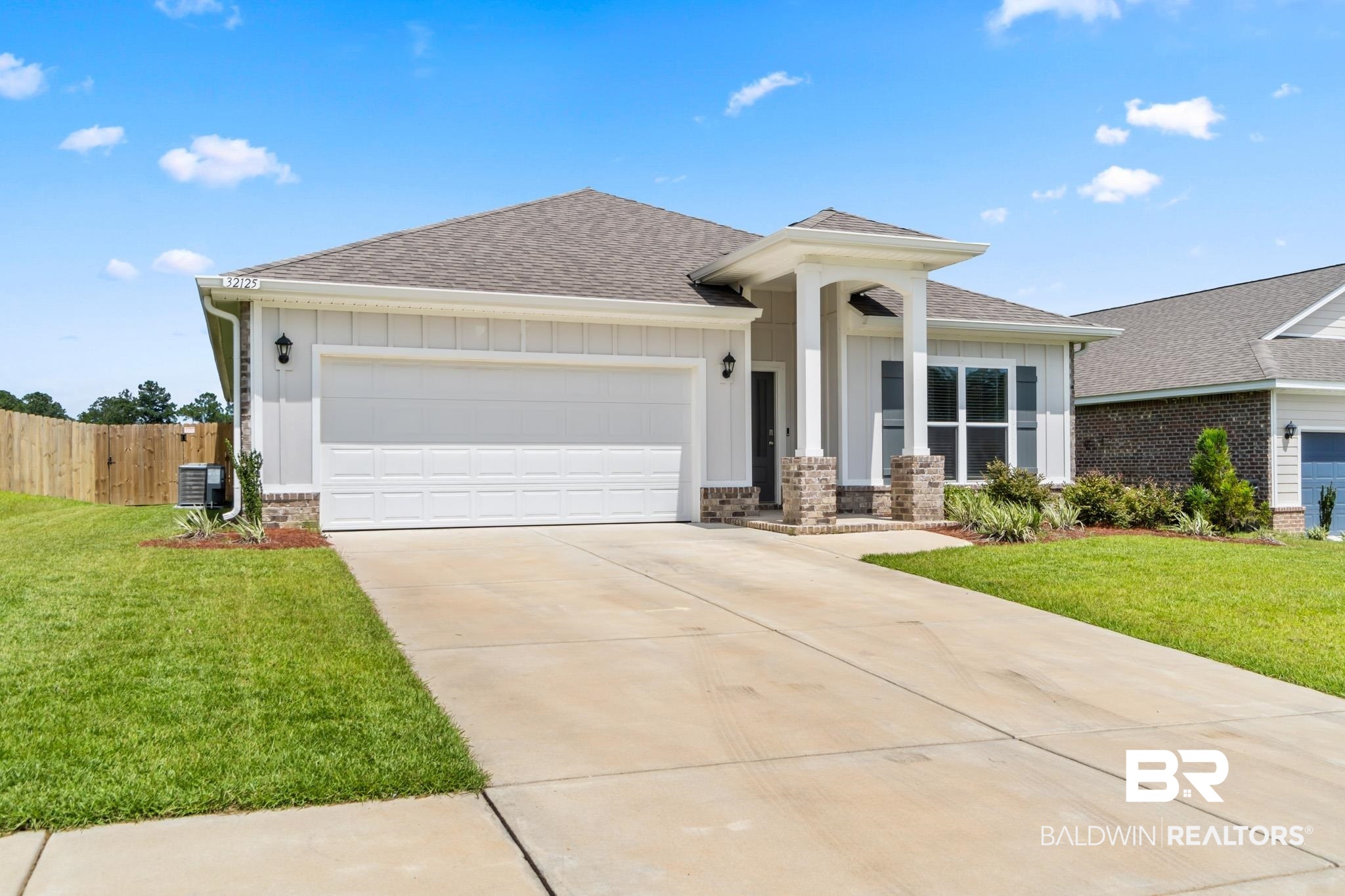 32125 Lyon Road Daphne, AL 36527 - Photo 2 of 70 Contemporary single-story residence featuring a two-car garage, board and batten siding, and a covered entry with stone-clad columns