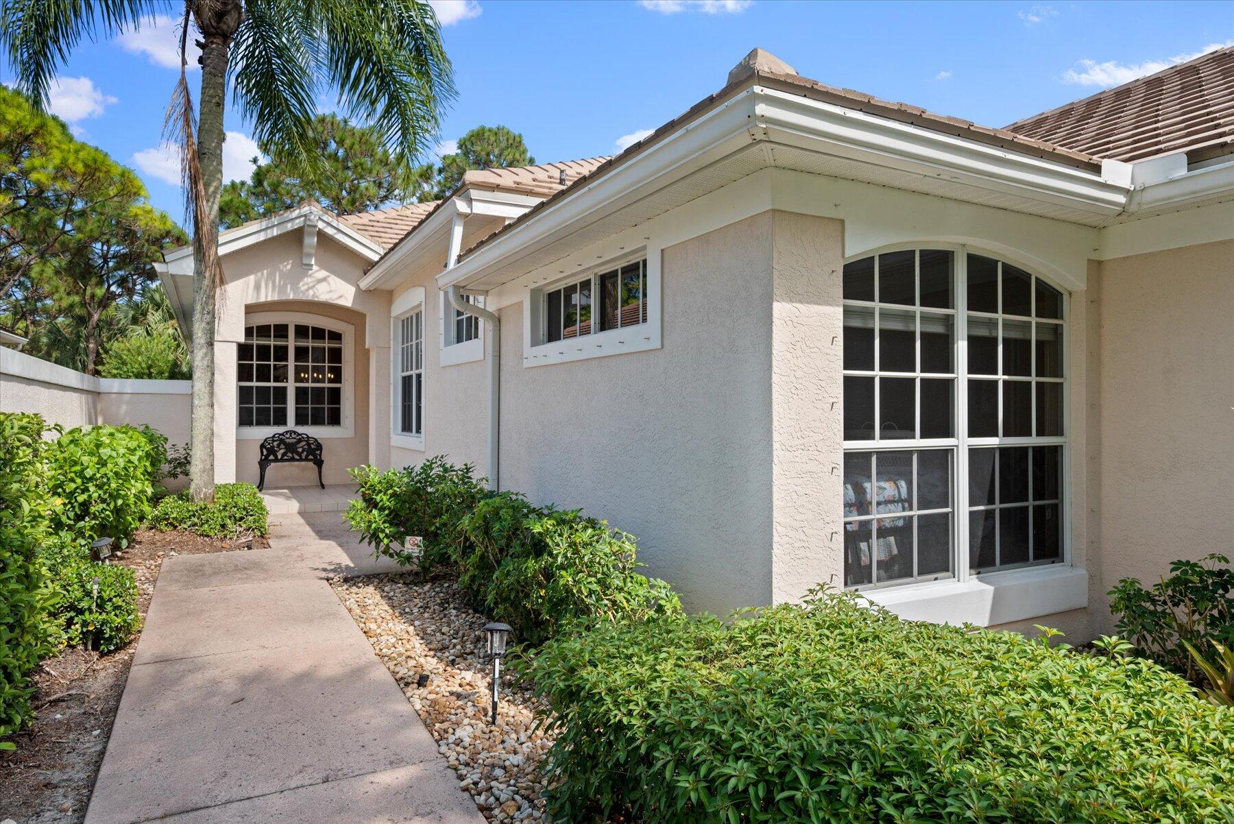3498 Southeast Doubleton Drive Stuart, FL 34997 - Photo 3 of 42 a view of a white house with large windows and plants