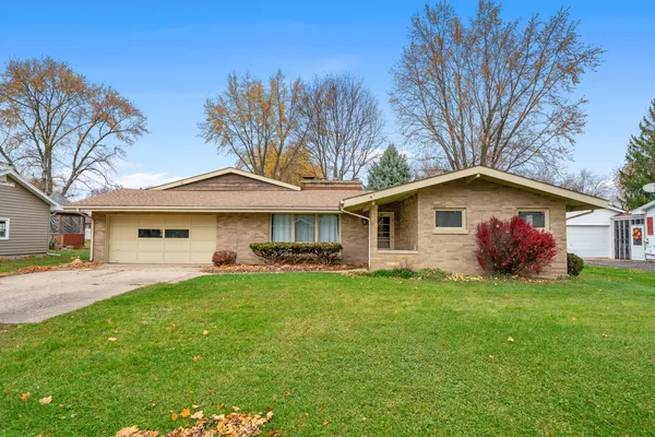 a front view of a house with a garden and trees
