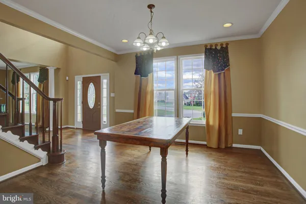 a dining room with wooden floor a chandelier a wooden table and chairs