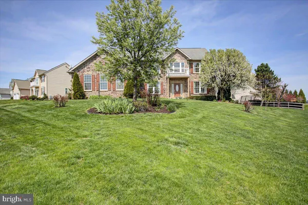 a view of a house next to a big yard and large trees