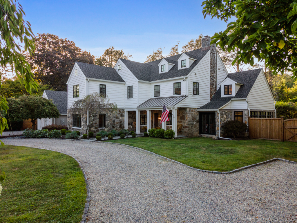 a view of a white house next to a yard with big trees