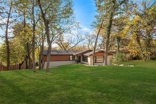 a house that is sitting in the grass with tress in the background