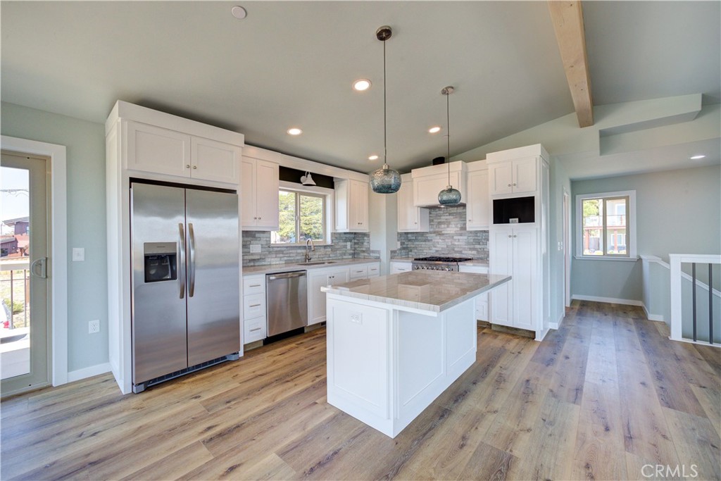 396 Castle Street Cambria, CA 93428 - Photo 22 of 74 a kitchen with stainless steel appliances granite countertop a refrigerator a sink dishwasher a stove and white countertops with wooden floor