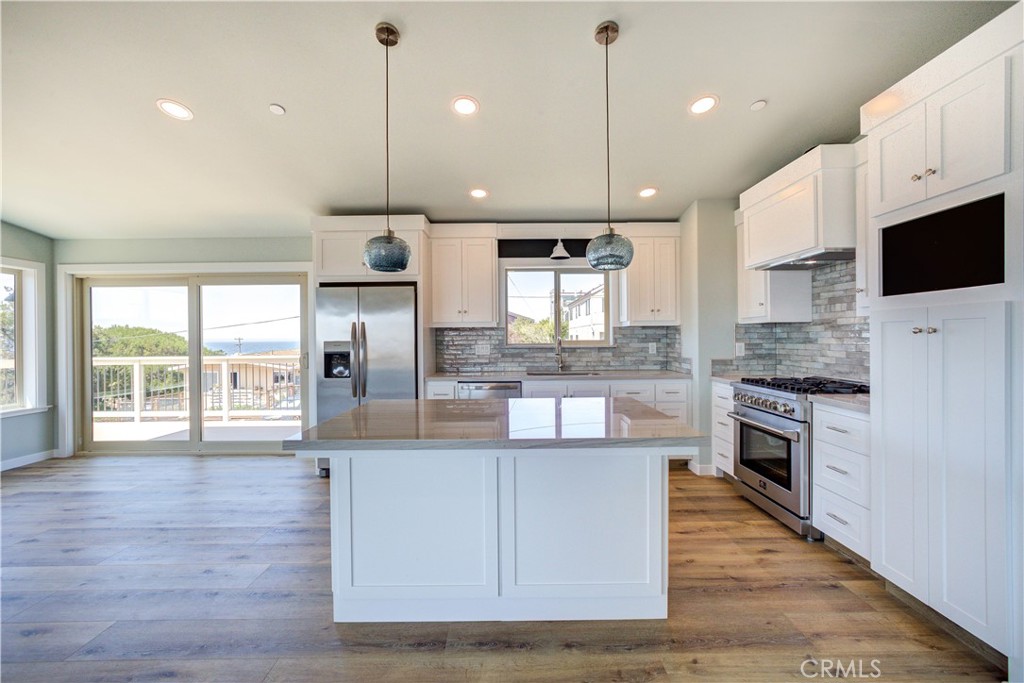 396 Castle Street Cambria, CA 93428 - Photo 23 of 74 a large kitchen with stainless steel appliances kitchen island granite countertop a stove a sink a refrigerator and a wooden floor