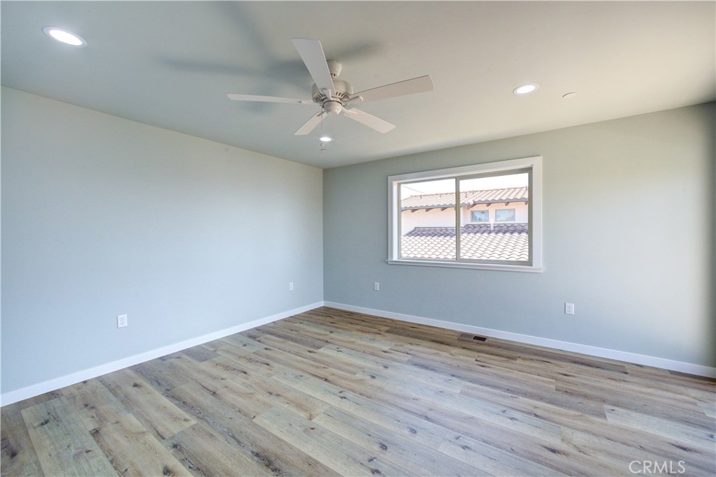 396 Castle Street Cambria, CA 93428 - Photo 30 of 74 an empty room with wooden floor ceiling fan and windows