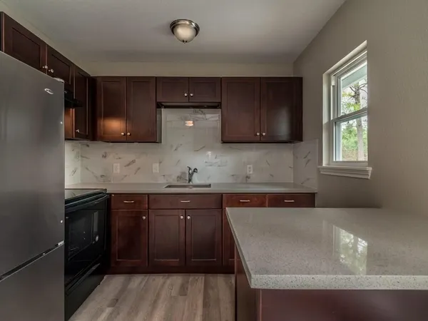 a kitchen with stainless steel appliances granite countertop wooden cabinets a refrigerator and a sink
