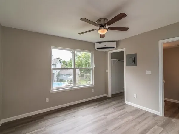 an empty room with wooden floor fan and windows