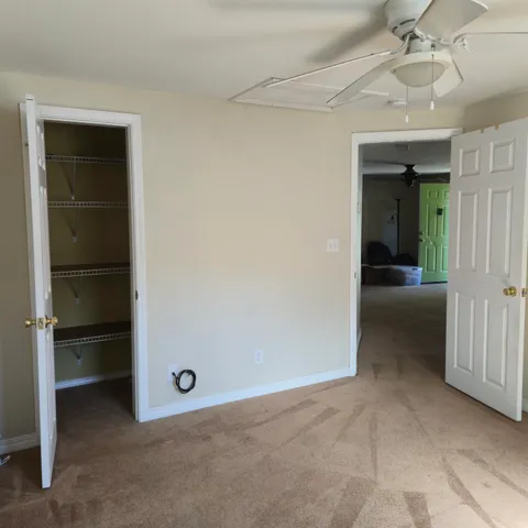 an empty room with closet and a chandelier fan