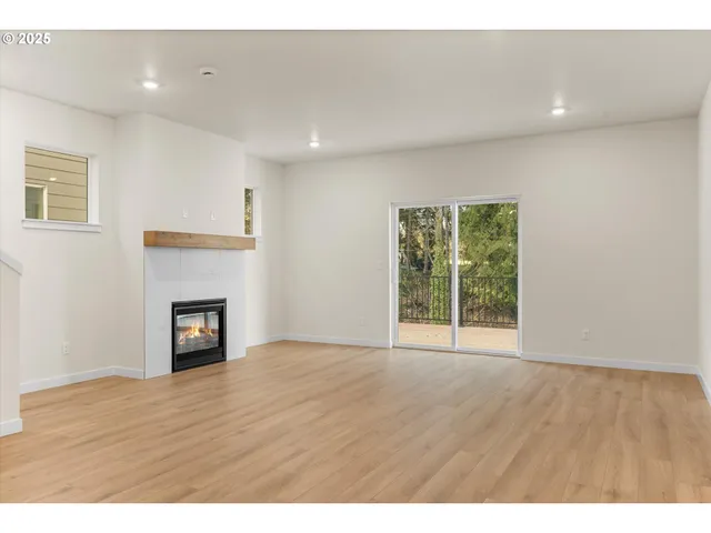 a view of a kitchen and an empty room with wooden floor