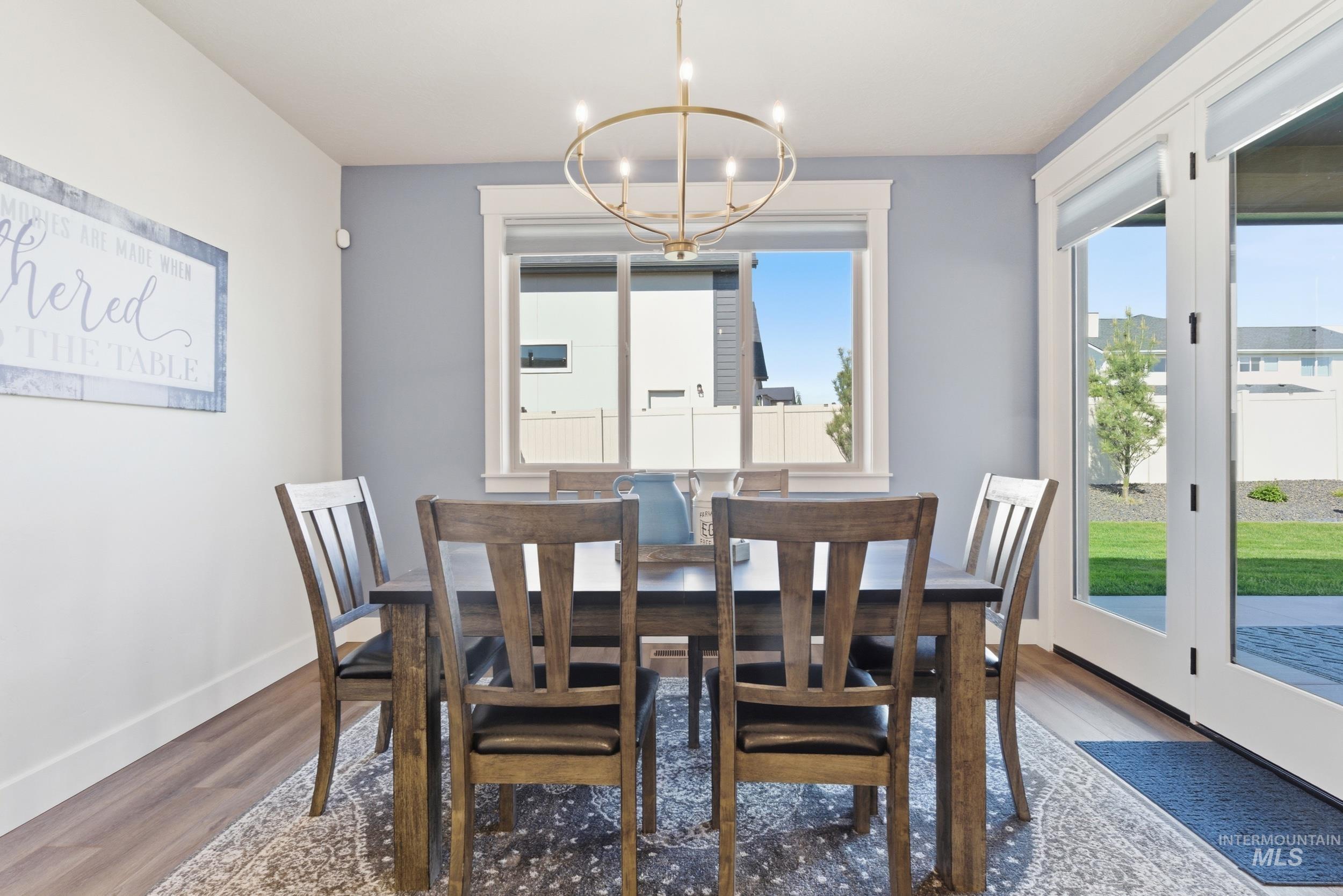 6347 South Utmost Lane Meridian, ID 83642 - Photo 13 of 37 Dining area featuring wood-finish flooring, a contemporary chandelier, and a window with white trim