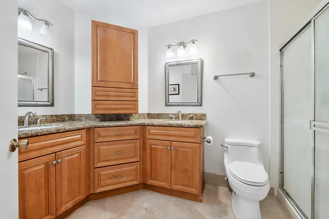 a bathroom with a granite countertop toilet sink and mirror