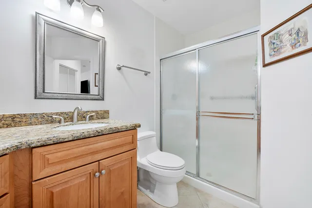 a bathroom with a granite countertop sink mirror vanity and toilet