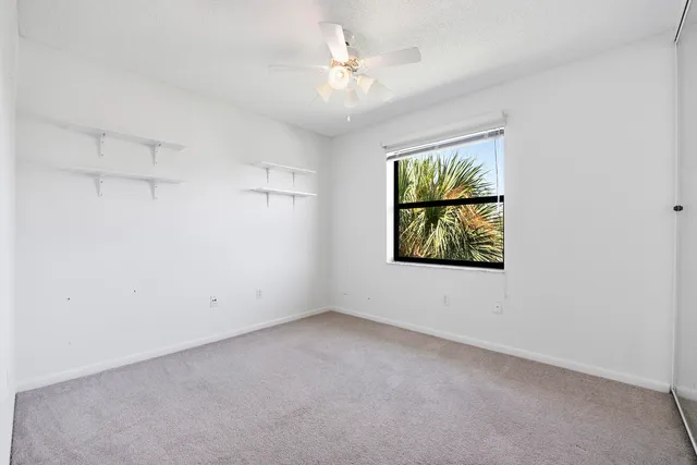 an empty room with windows and fan