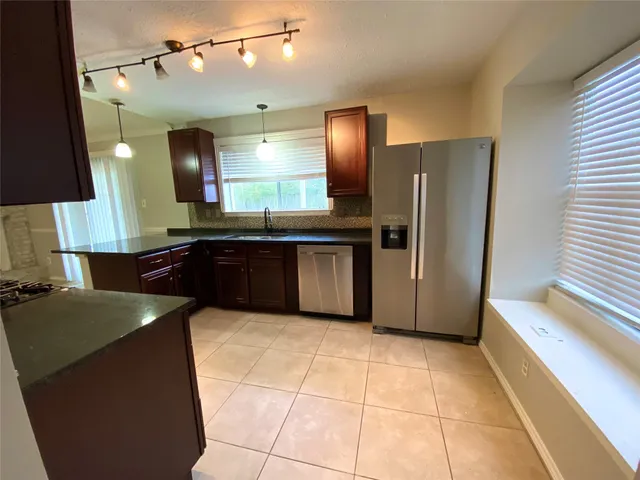 a kitchen with stainless steel appliances granite countertop a refrigerator a sink and a stove