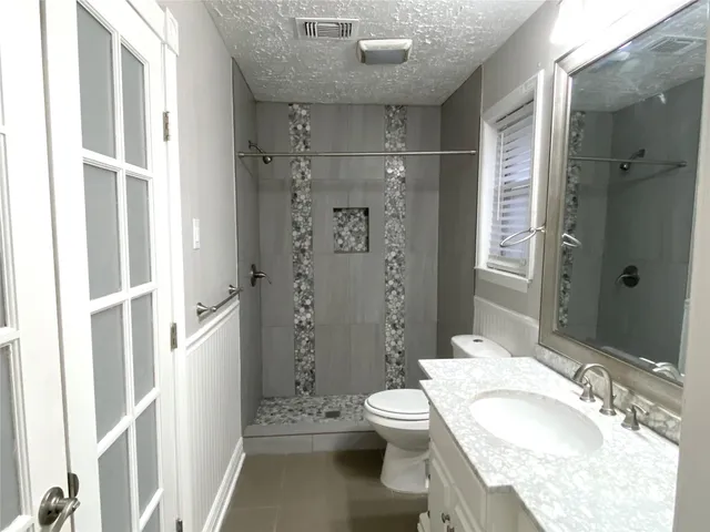 a bathroom with a granite countertop sink toilet and shower