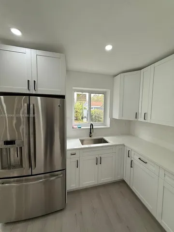 a kitchen with stainless steel appliances granite countertop a refrigerator a sink and white cabinets