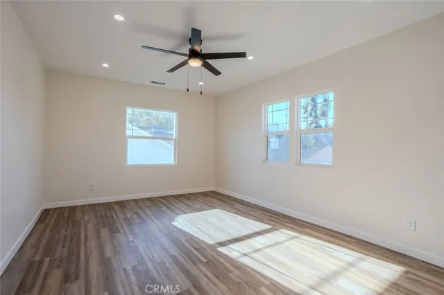 a view of empty room with wooden floor and fan
