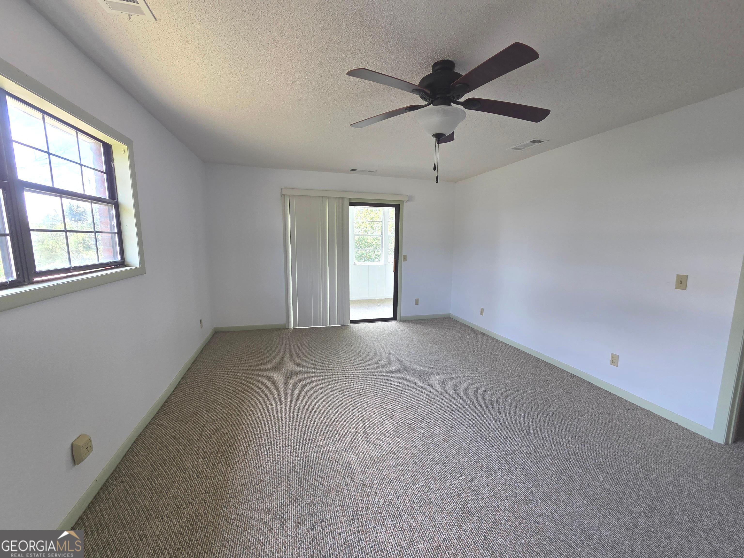 674 McNatt Falls Road Uvalda, GA 30473 - Photo 33 of 58 an empty room with a ceiling fan and windows