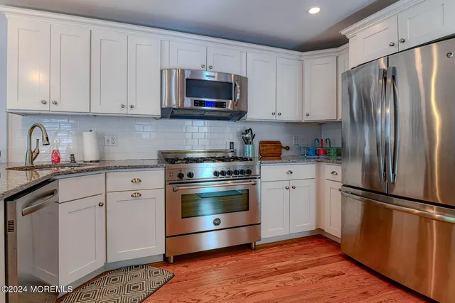 a kitchen with cabinets stainless steel appliances and wooden floor