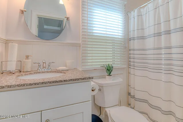 a bathroom with a granite countertop toilet sink and mirror