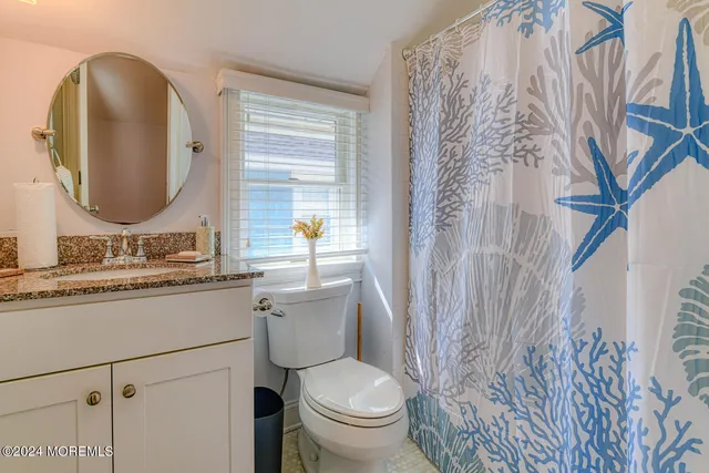 a bathroom with a granite countertop toilet sink and mirror