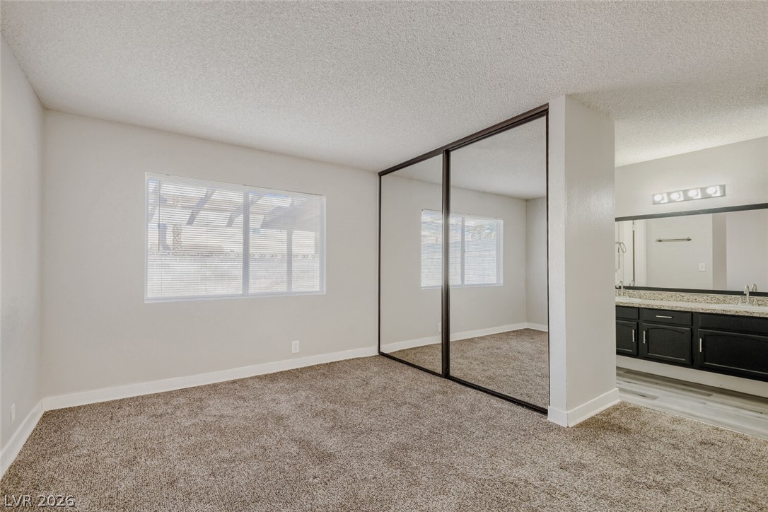 2343 Valleywood Road Henderson, NV 89014 - Photo 11 of 29 Ample natural light illuminates this bedroom, offering mirrored closet doors and a vanity.