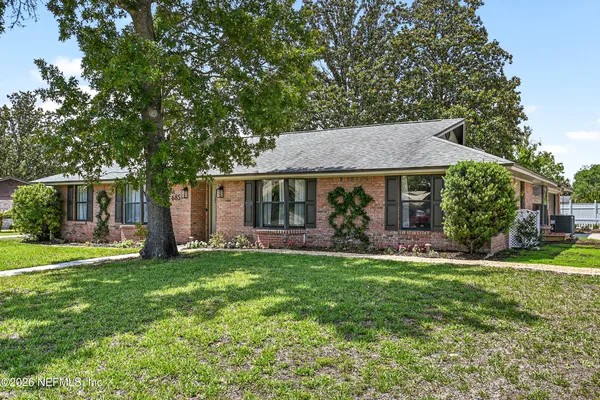 a front view of a house with a garden and trees