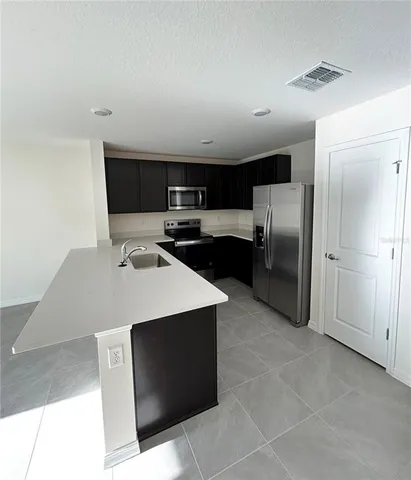 a kitchen with stainless steel appliances a refrigerator a stove a sink and a refrigerator