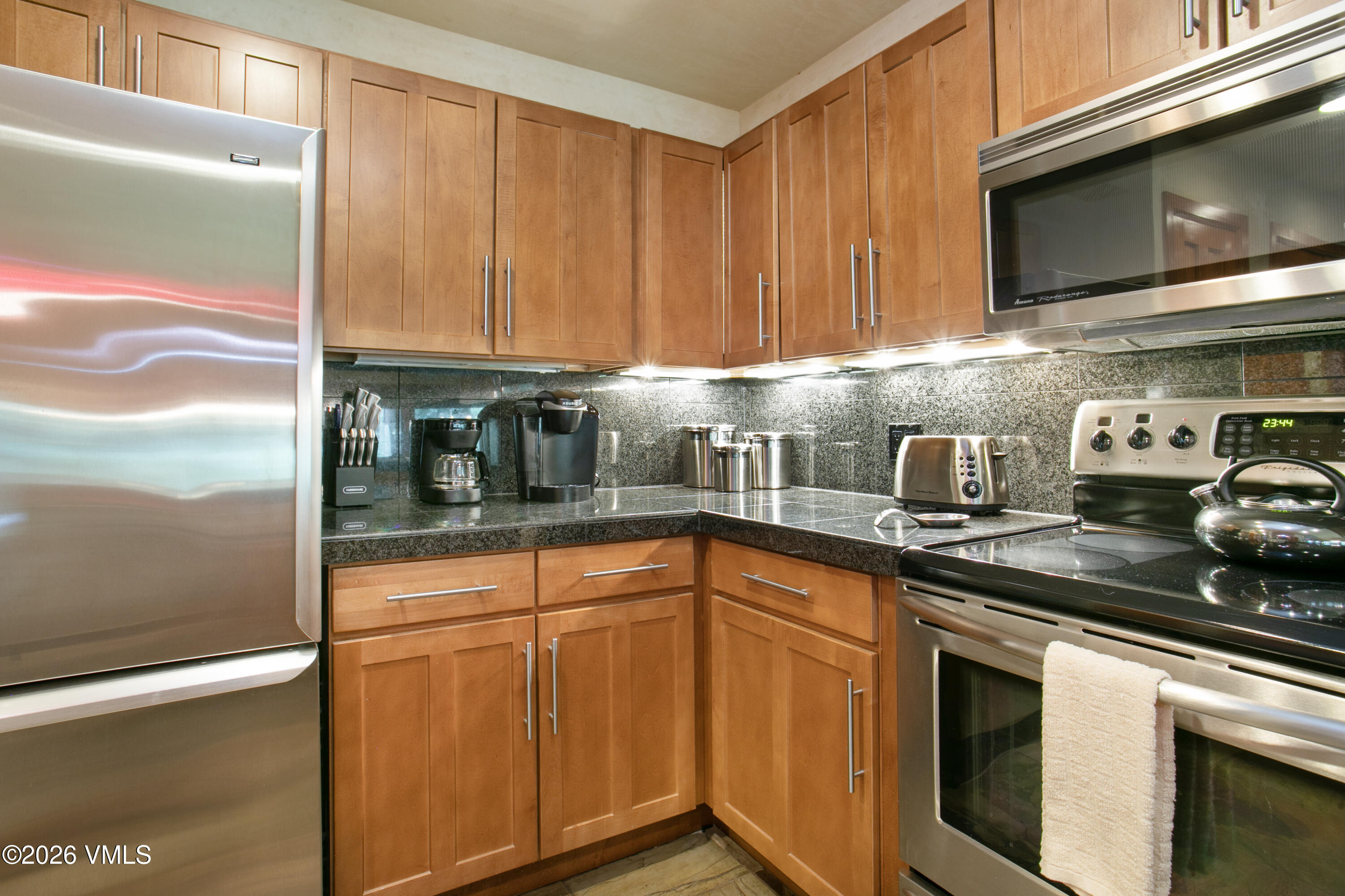 3911 Big Horn Road, Unit 1B Vail, CO 81657 - Photo 3 of 29 a kitchen with stainless steel appliances granite countertop a sink a stove microwave and cabinets