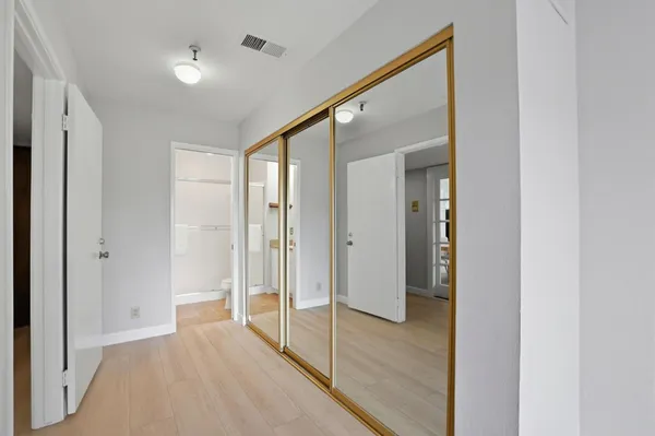a view of a hallway with wooden floor and closet