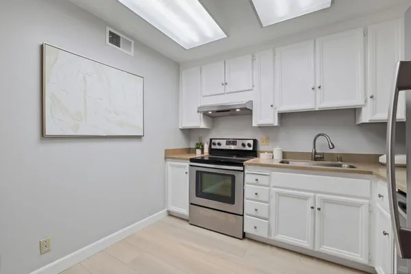 a kitchen with stainless steel appliances granite countertop white cabinets a stove a sink and dishwasher