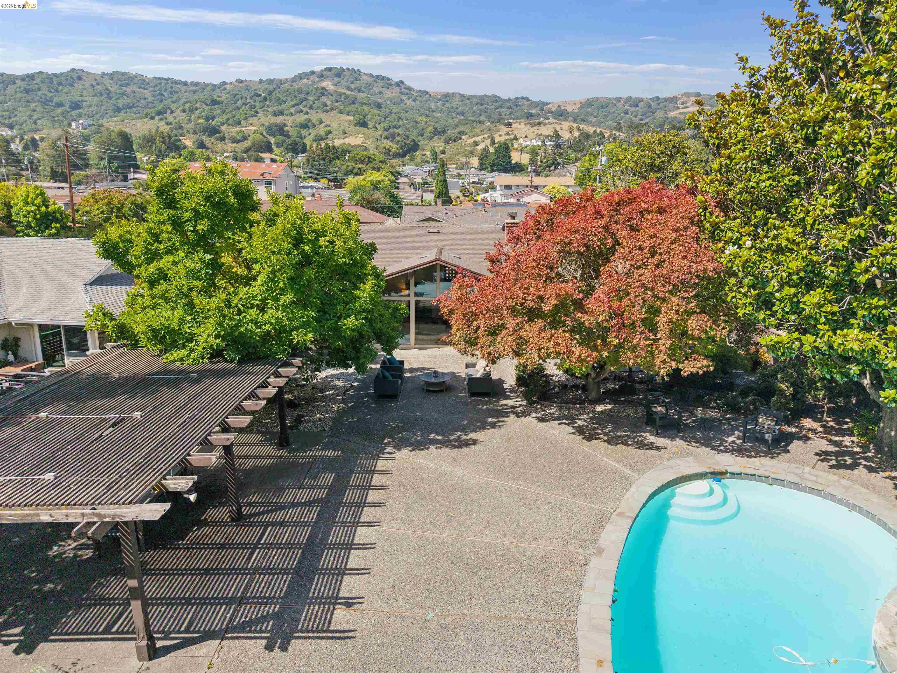 7 Jo Lin Court El Sobrante, CA 94803 - Photo 11 of 99 Expansive outdoor area featuring a freeform swimming pool, an exposed aggregate patio, a large pergola, and mature trees providing natural shade