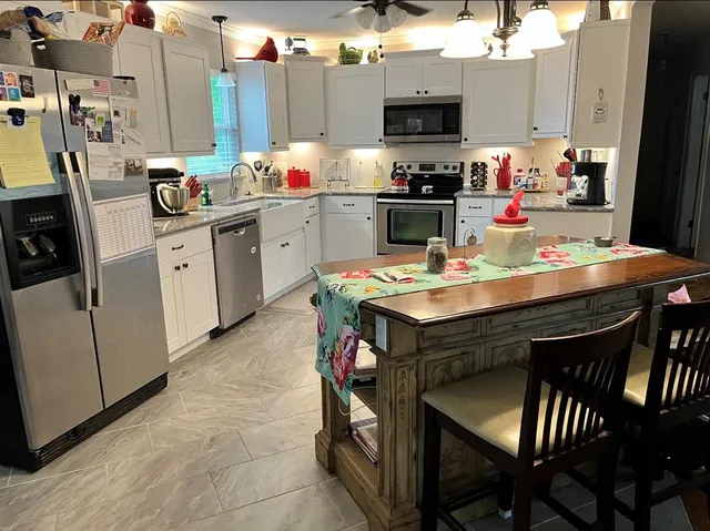 a kitchen with stainless steel appliances a sink a stove a table and chairs